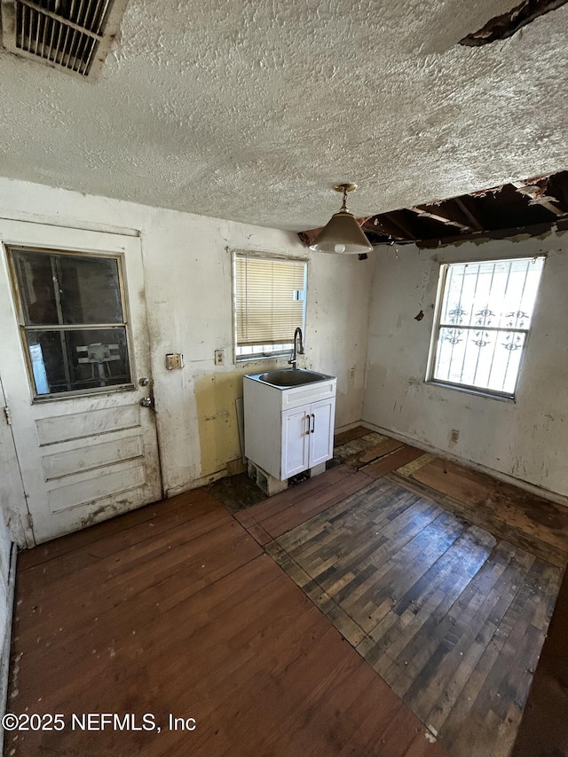 interior space with white cabinetry, dark hardwood / wood-style flooring, sink, and a textured ceiling