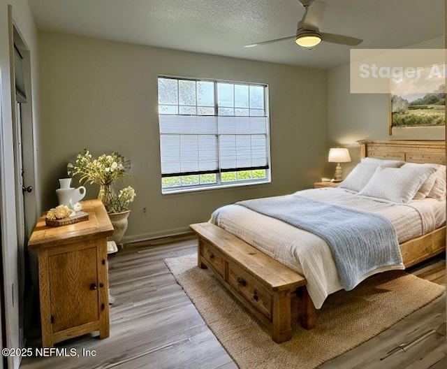 bedroom with ceiling fan, a textured ceiling, and light hardwood / wood-style floors