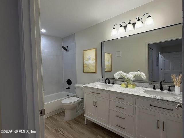 full bathroom featuring hardwood / wood-style flooring, tiled shower / bath, vanity, and toilet