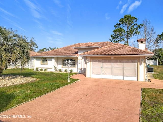 mediterranean / spanish-style house featuring a garage, a front yard, and central air condition unit