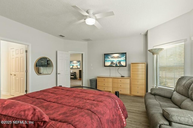 bedroom with ceiling fan, wood-type flooring, and a textured ceiling