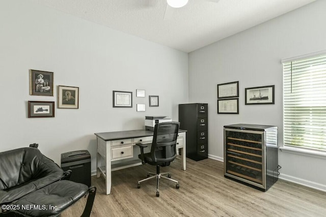 office space with ceiling fan, beverage cooler, and light wood-type flooring