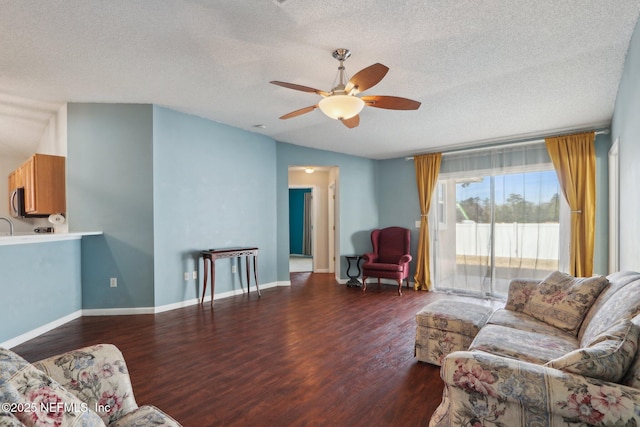 living room featuring ceiling fan, dark hardwood / wood-style floors, and a textured ceiling