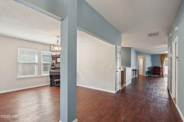 interior space featuring dark wood-type flooring, a textured ceiling, and a notable chandelier