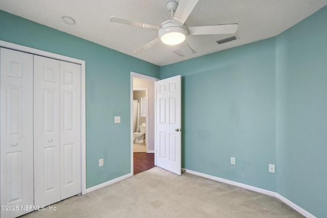 unfurnished bedroom featuring ceiling fan, light colored carpet, a closet, and a textured ceiling