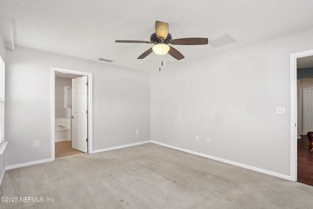 unfurnished bedroom with ceiling fan, ensuite bathroom, light carpet, and a textured ceiling