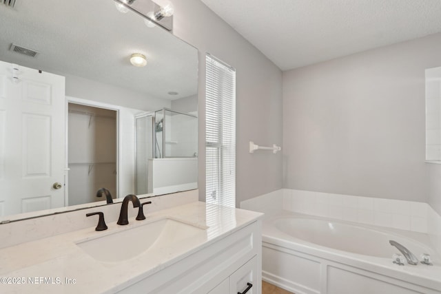 bathroom with vanity, plus walk in shower, and a textured ceiling