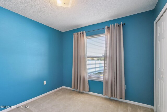 unfurnished room featuring light colored carpet and a textured ceiling