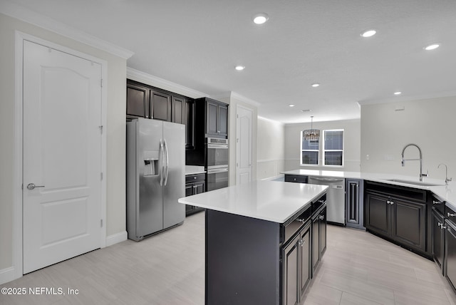 kitchen with sink, crown molding, appliances with stainless steel finishes, a kitchen island, and pendant lighting