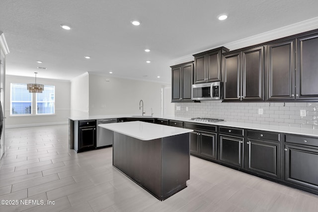 kitchen featuring hanging light fixtures, appliances with stainless steel finishes, kitchen peninsula, a kitchen island, and backsplash