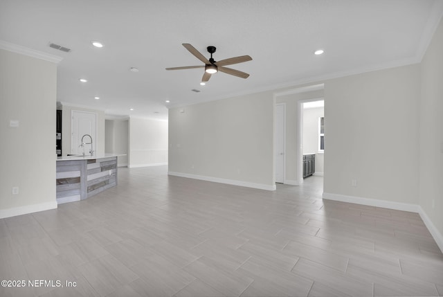 unfurnished living room featuring ceiling fan, ornamental molding, and sink