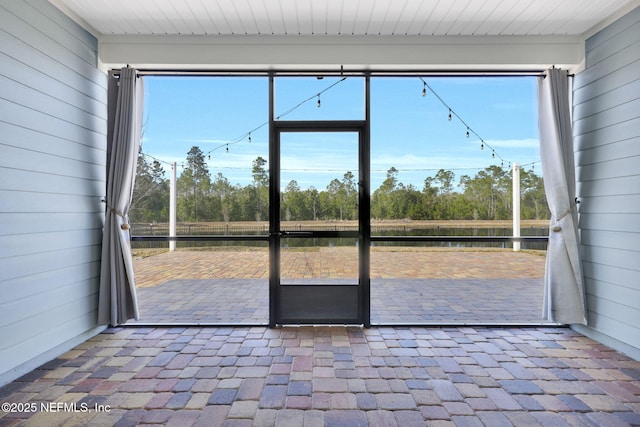 doorway featuring a wealth of natural light, wooden walls, and a water view