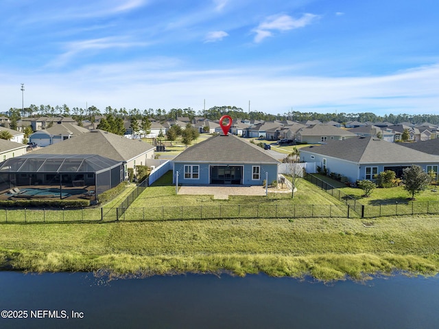 rear view of property featuring a water view, a lanai, and a lawn