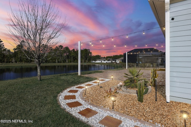 yard at dusk with a water view and a patio area