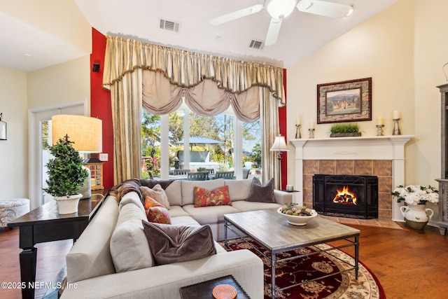 living room featuring a tiled fireplace, hardwood / wood-style floors, vaulted ceiling, and ceiling fan