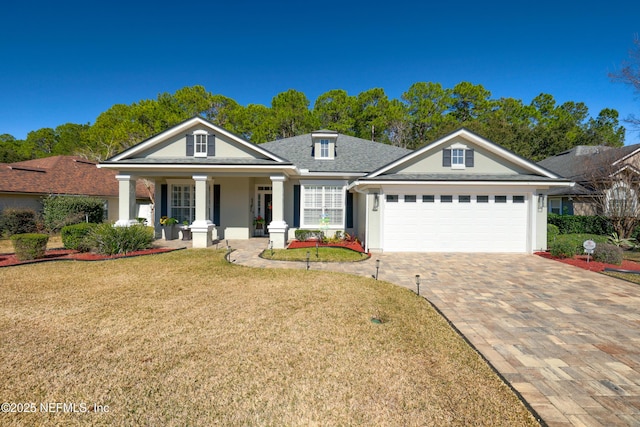 view of front of home featuring a garage, a front lawn, and covered porch