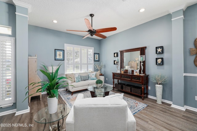 living room with ornate columns, dark wood-type flooring, a textured ceiling, and ceiling fan