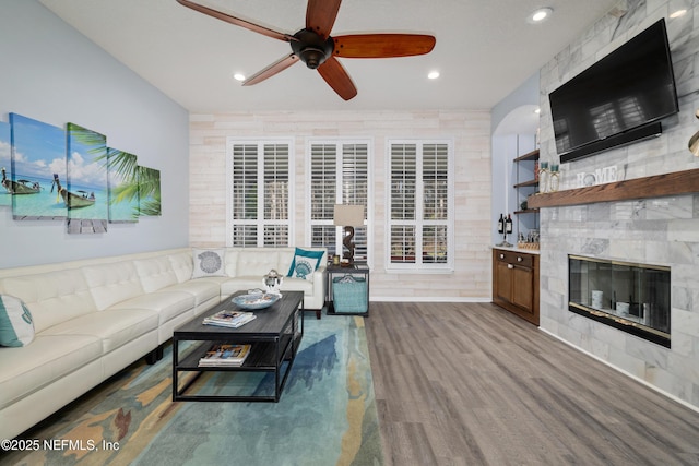 living room featuring wood-type flooring, ceiling fan, and a high end fireplace