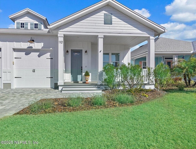 view of front of property with a garage, a front yard, and covered porch