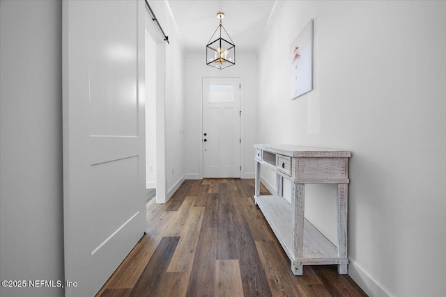 entryway with dark wood-type flooring, a barn door, and a notable chandelier