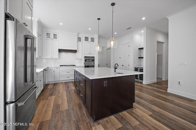 kitchen featuring appliances with stainless steel finishes, wine cooler, white cabinets, backsplash, and a center island with sink