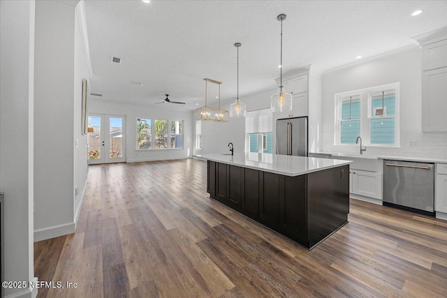 kitchen featuring white cabinetry, appliances with stainless steel finishes, a center island, and hanging light fixtures