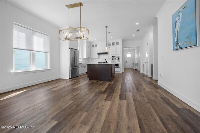 kitchen featuring white cabinetry, high end refrigerator, hanging light fixtures, ornamental molding, and a kitchen island