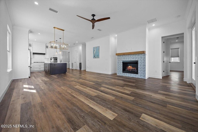 unfurnished living room featuring crown molding, dark wood-type flooring, and ceiling fan