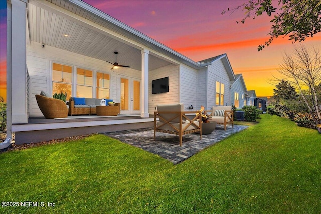 rear view of property featuring a patio, a lawn, ceiling fan, an outdoor living space, and french doors