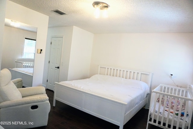 bedroom with a closet, dark hardwood / wood-style floors, and a textured ceiling