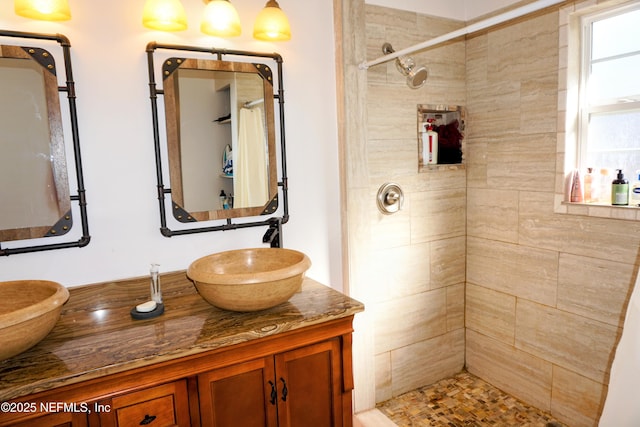 bathroom with tiled shower and vanity