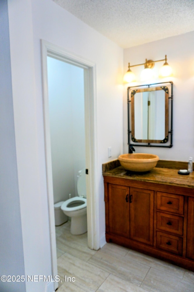 bathroom with vanity, a textured ceiling, and toilet