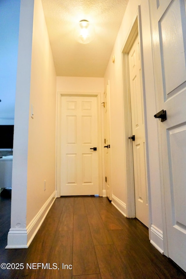 hallway with dark wood-type flooring and a textured ceiling