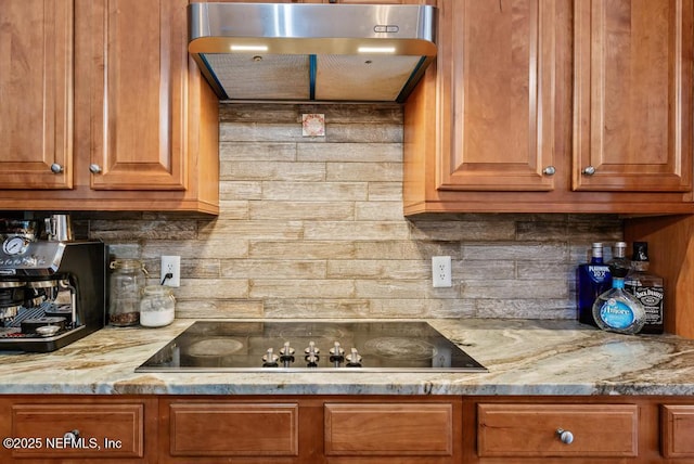 kitchen featuring light stone countertops, brown cabinets, black electric stovetop, and extractor fan