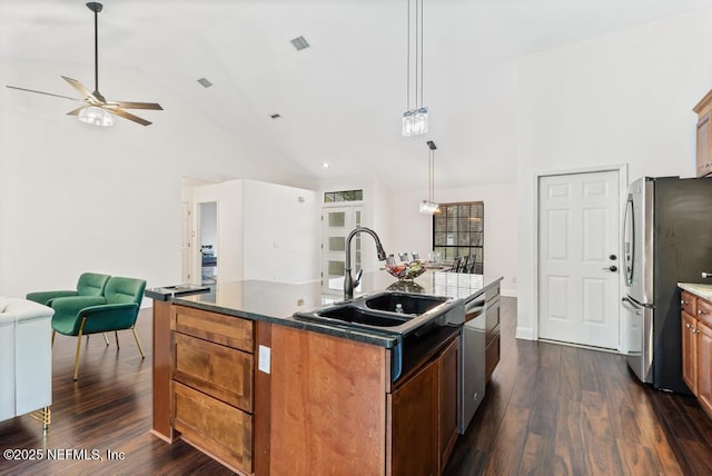 kitchen featuring a kitchen island with sink, open floor plan, appliances with stainless steel finishes, dark wood-style floors, and decorative light fixtures