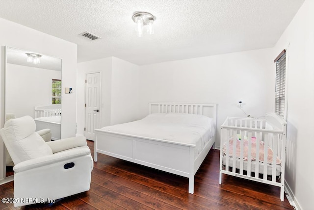 bedroom featuring dark wood-style floors, visible vents, and a textured ceiling