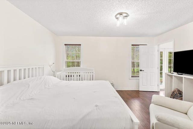 bedroom featuring dark wood-style flooring, multiple windows, and a textured ceiling