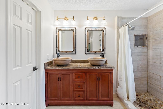 full bathroom featuring a stall shower, a sink, and a textured ceiling