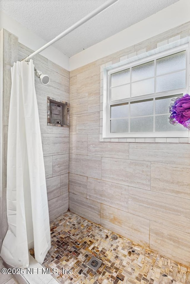 full bath featuring a textured ceiling and tiled shower