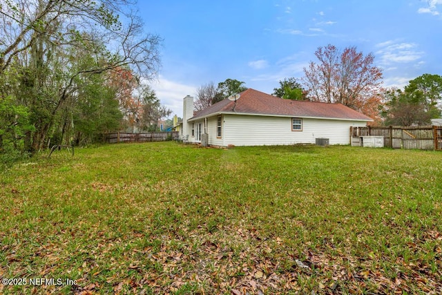 exterior space with a yard, central AC unit, a chimney, and a fenced backyard