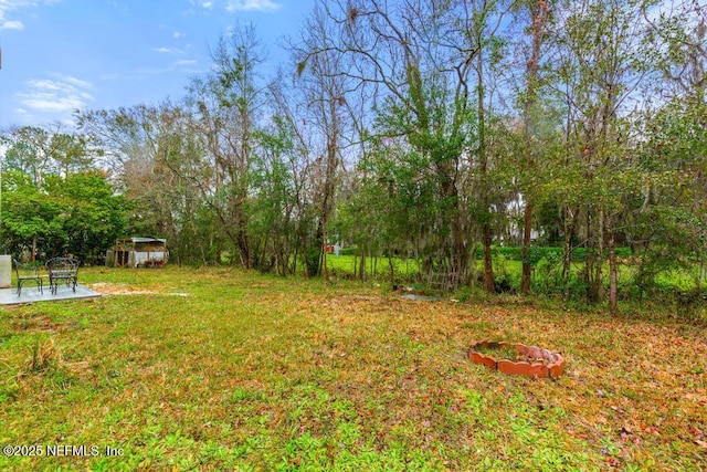 view of yard featuring an outdoor fire pit and a patio area