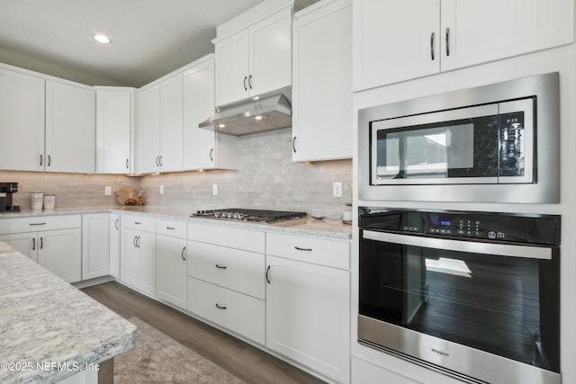 kitchen with light stone countertops, white cabinetry, appliances with stainless steel finishes, and tasteful backsplash