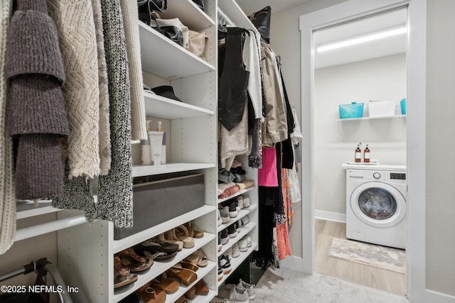 walk in closet with washer / dryer and light hardwood / wood-style flooring