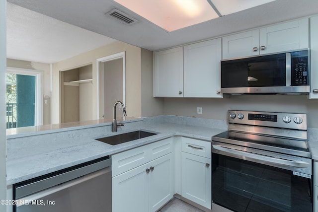 kitchen featuring sink, stainless steel appliances, white cabinets, and light stone countertops