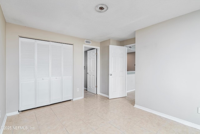 unfurnished bedroom featuring light tile patterned floors, a textured ceiling, and a closet