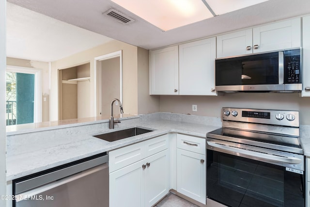 kitchen featuring stainless steel appliances, white cabinetry, sink, and light stone counters