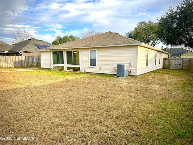 rear view of property with central AC unit and a lawn