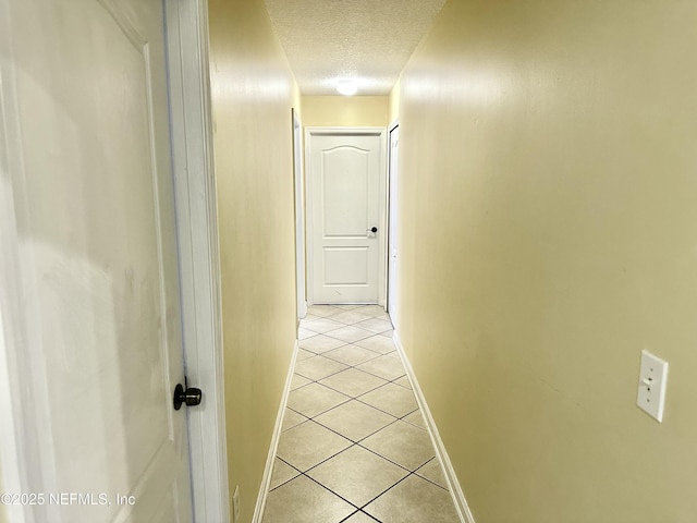 corridor featuring a textured ceiling and light tile patterned flooring