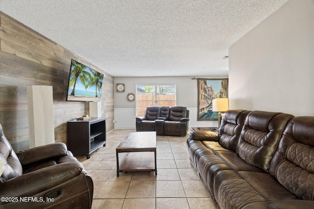 living room featuring light tile patterned floors, wooden walls, and a textured ceiling