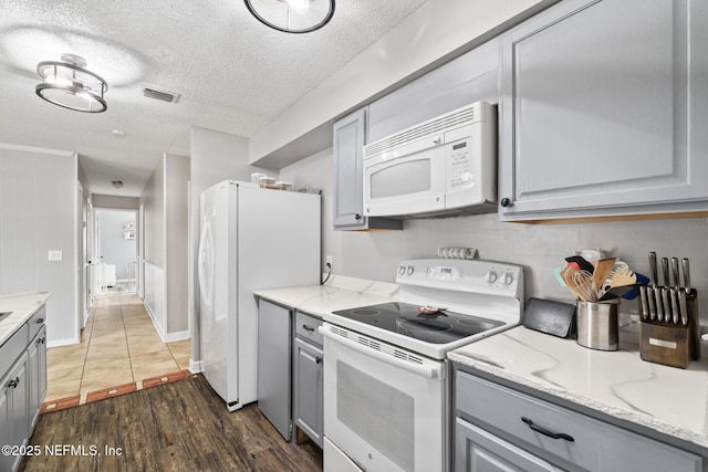 kitchen featuring dark wood-type flooring, white appliances, a textured ceiling, and gray cabinetry